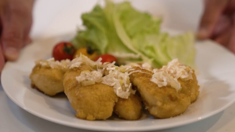 Plate of oven-baked chicken karaage topped with chopped onions, served with lettuce and cherry tomatoes