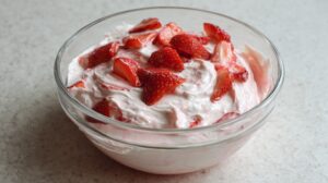 Glass bowl filled with strawberries mixed into sweet cream