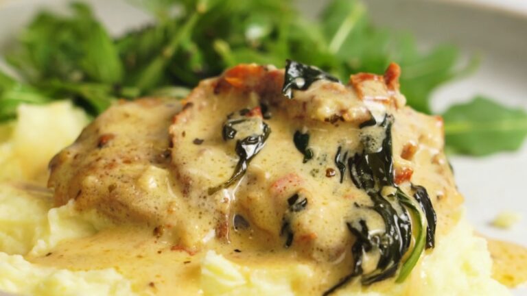Creamy Tuscan Chicken served over mashed potatoes with spinach, sun-dried tomatoes, and a side of fresh greens