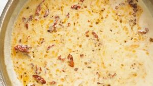 Cream, sun-dried tomatoes, and seasoning simmering together in a skillet to form the sauce