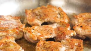 Seared chicken thighs simmering in a pan to finish cooking through
