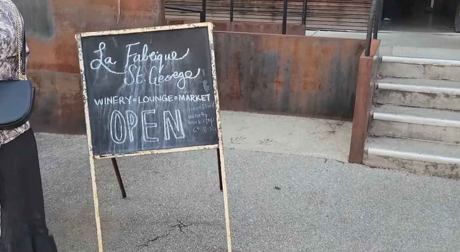 Chalkboard sign outside La Fabrique St. George winery, lounge, and market with 'OPEN' written on it.