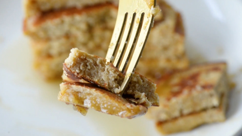 A close-up of a fork holding a bite of soft, fluffy chickpea flour pancake with more sliced pieces on the plate below
