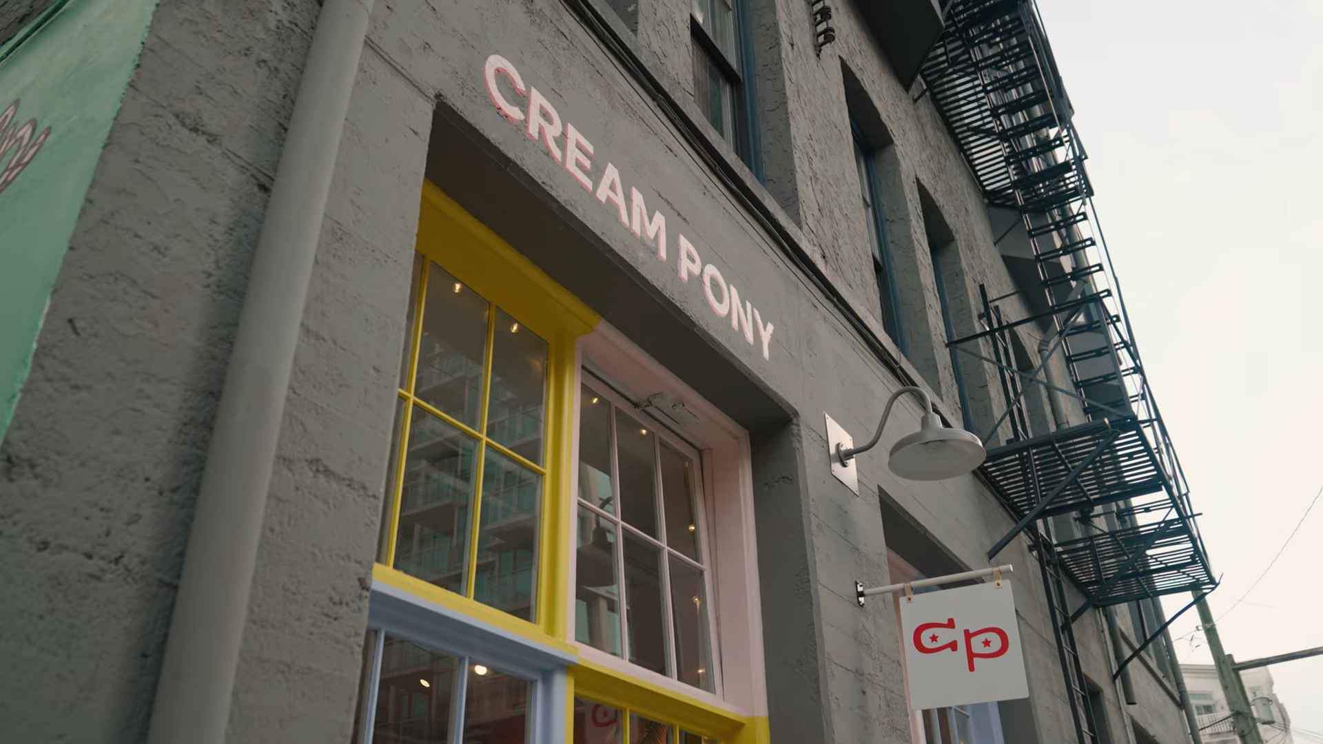 Exterior of Cream Pony café with a yellow-framed window and hanging sign