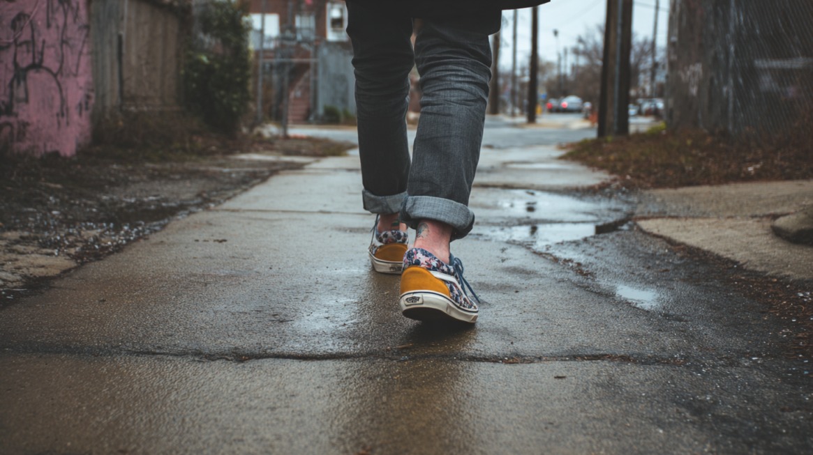 Person walking along a wet sidewalk in casual shoes