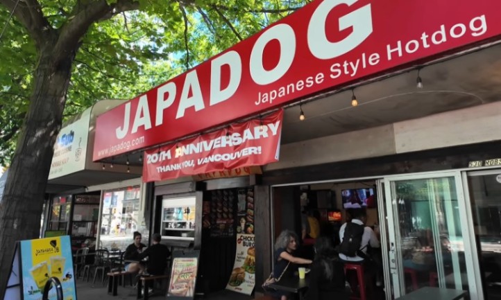 Outdoor view of Japadog, a Japanese-style hotdog shop. Red sign with white letters