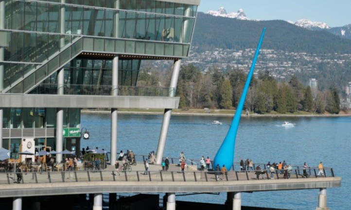Modern waterfront building with glass facade, people strolling