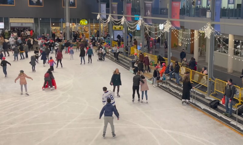 Indoor ice rink scene with people of all ages skating