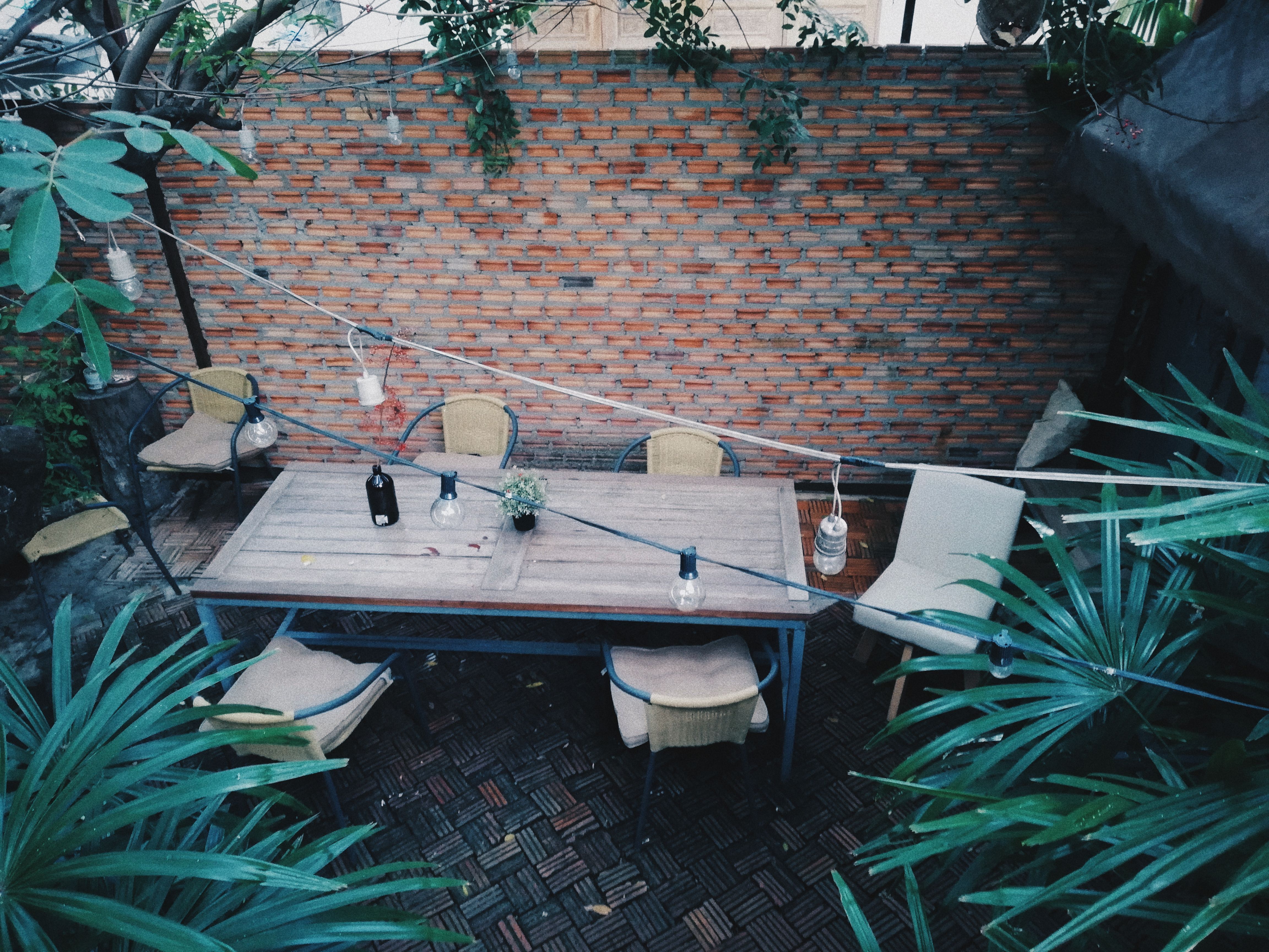 Cozy outdoor patio with wooden table and chairs against a rustic brick wall