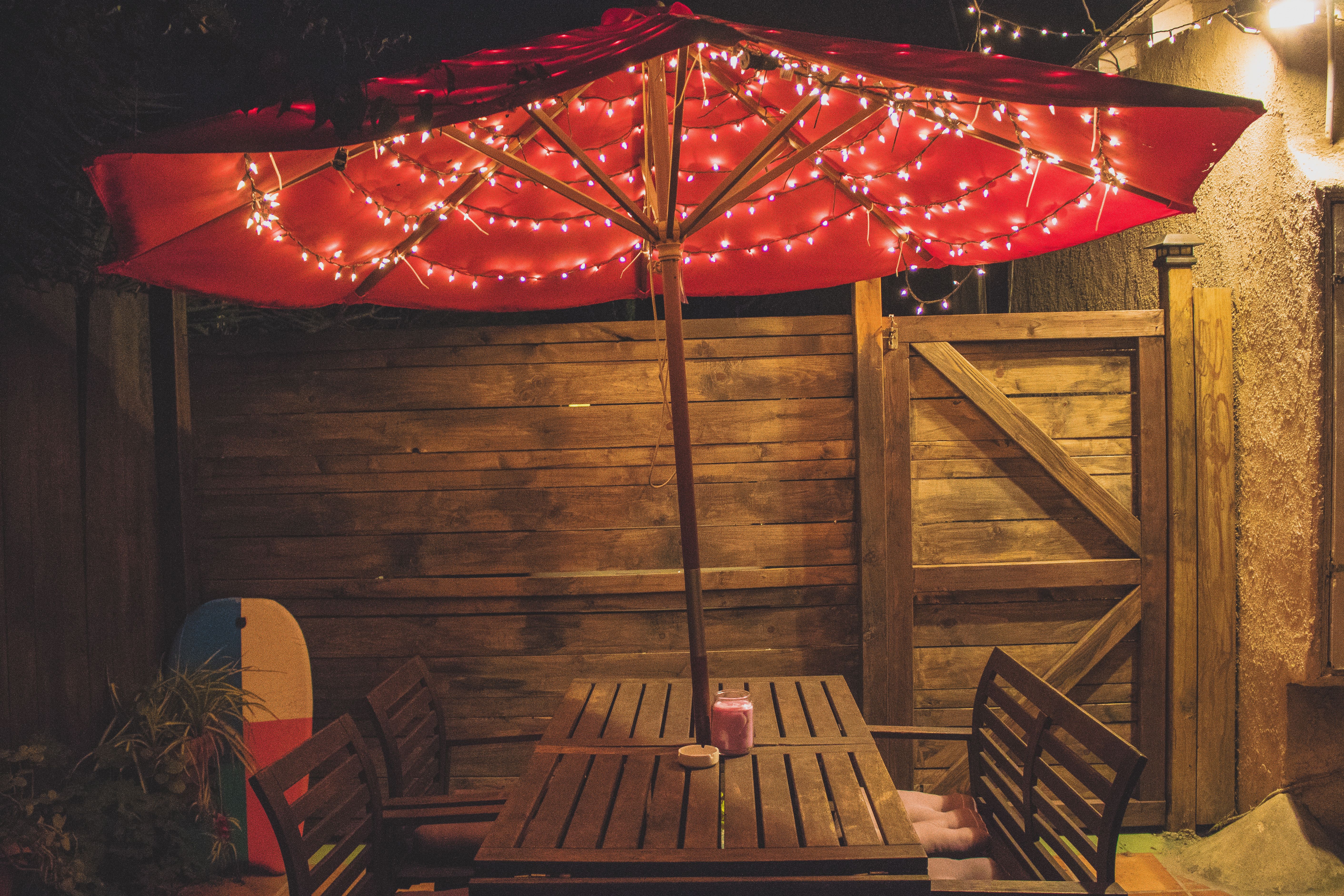 Outdoor dining setup with a red parasol and string lights for evening gatherings