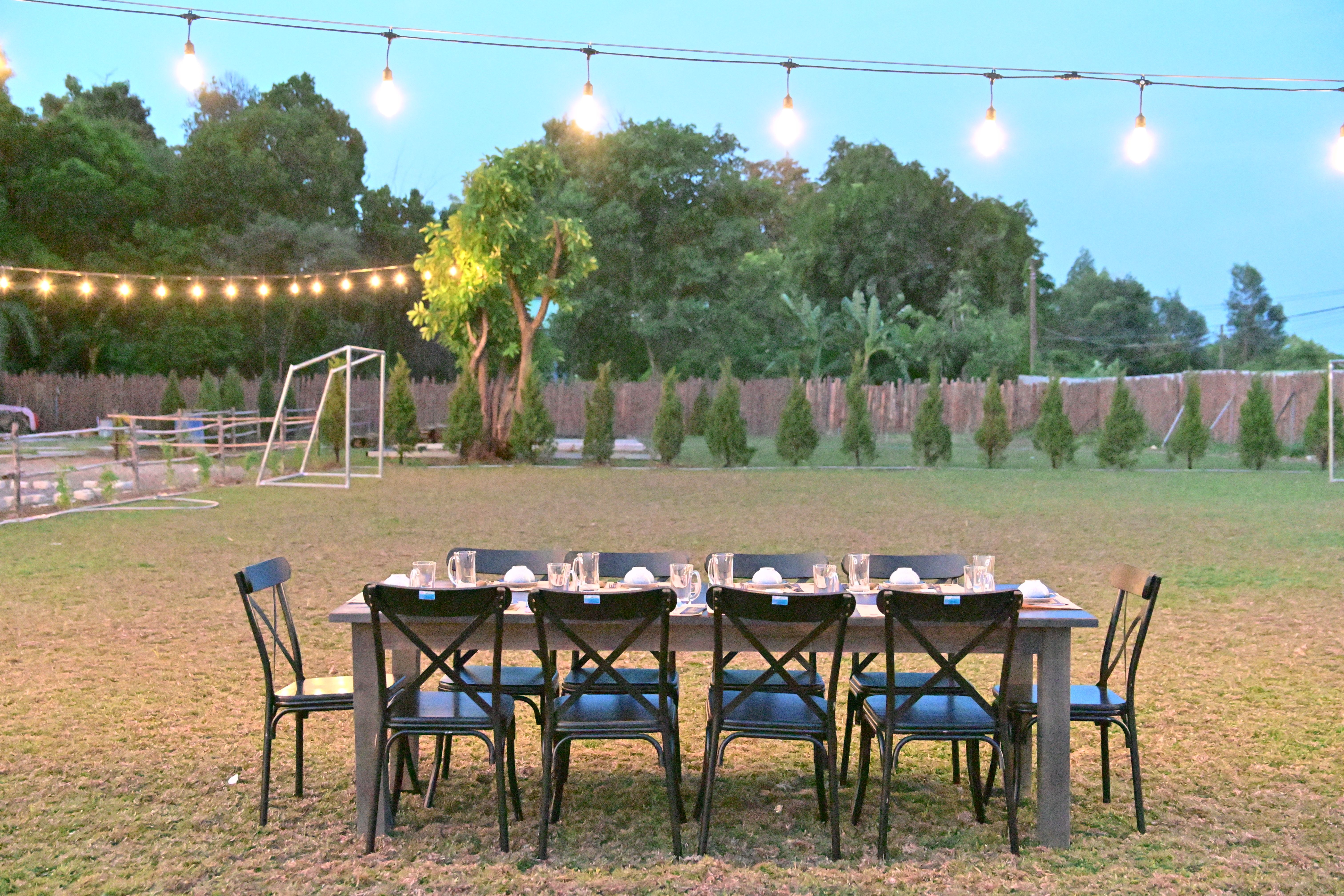 Outdoor dinner table set up under string lights for an evening gathering